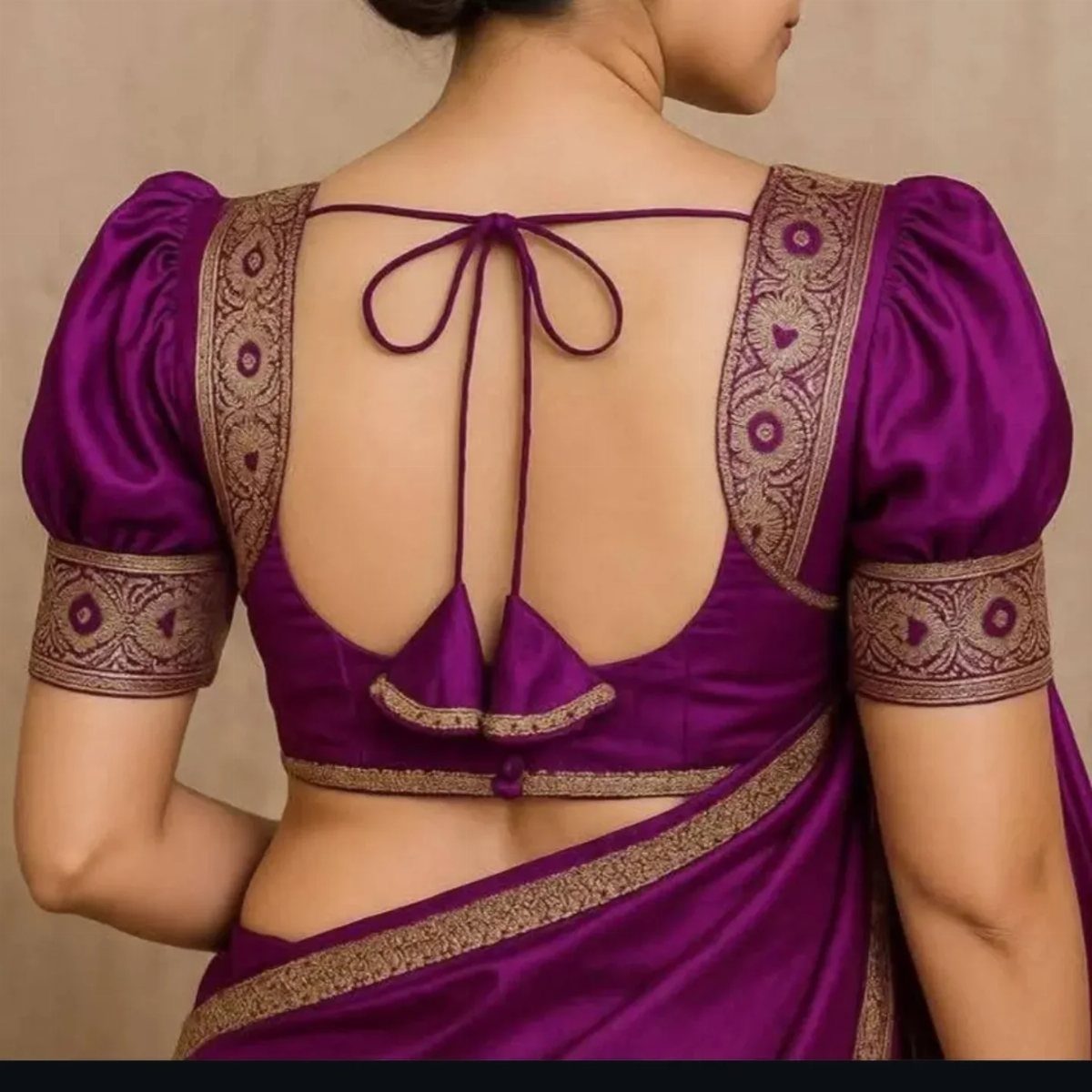 Woman wearing a purple silk blouse with gold embroidery and puff sleeves.