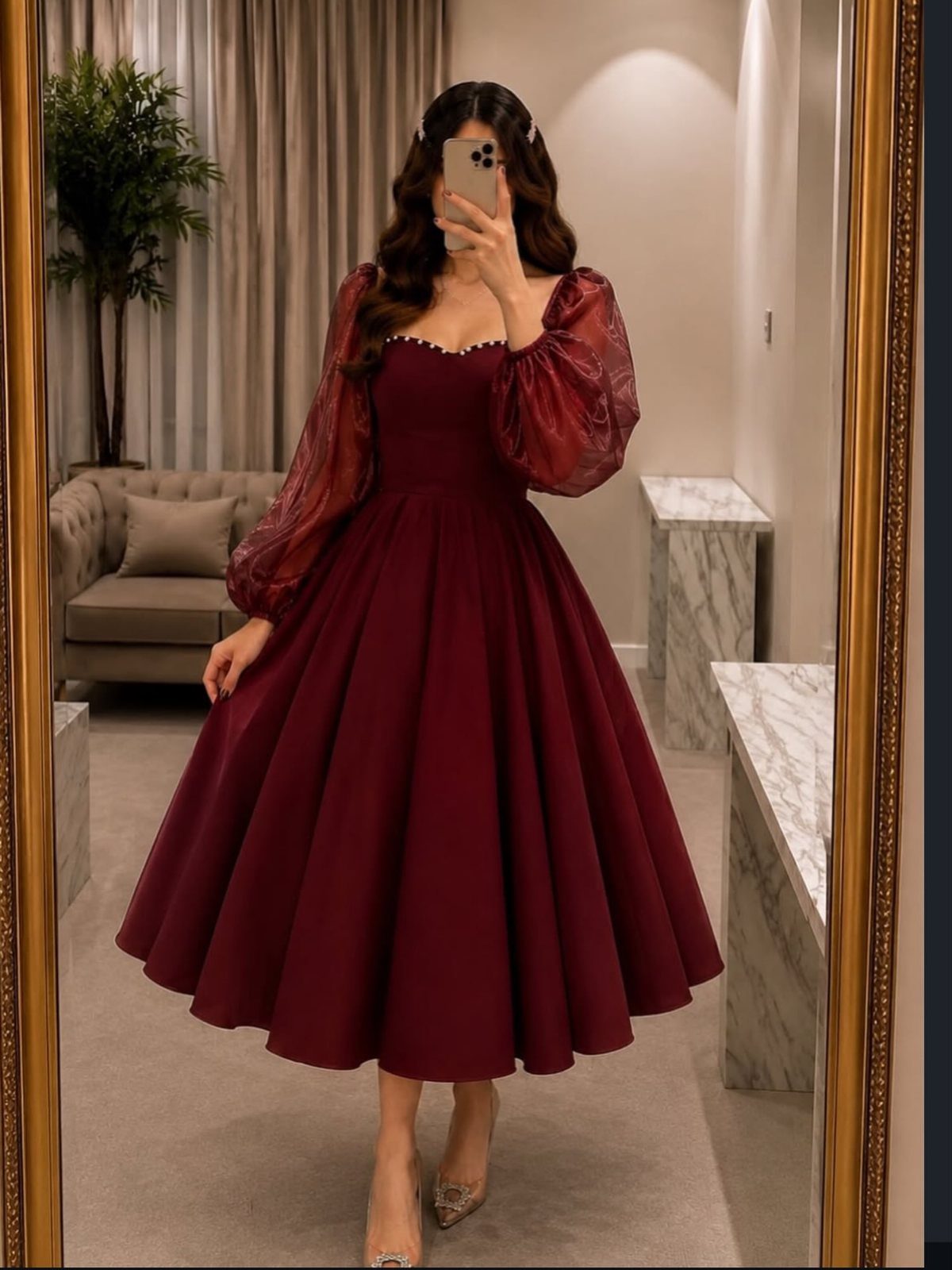 Woman in a burgundy fit-and-flare dress with puff sleeves posing for a mirror selfie.