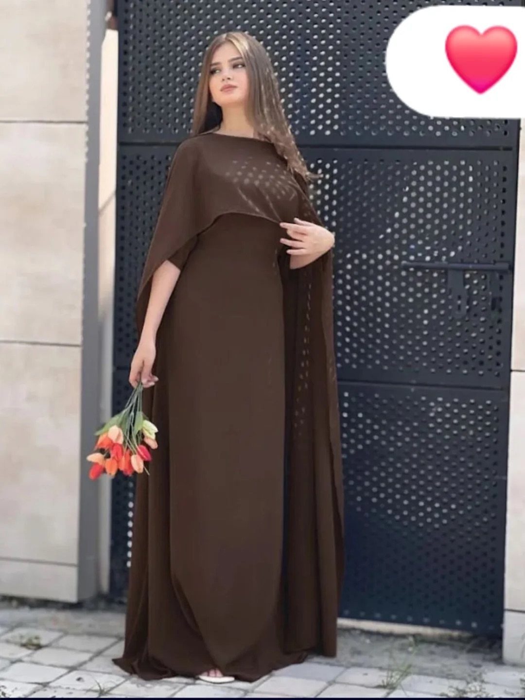 A woman in a long brown gown with a matching draped shawl holding tulips.
