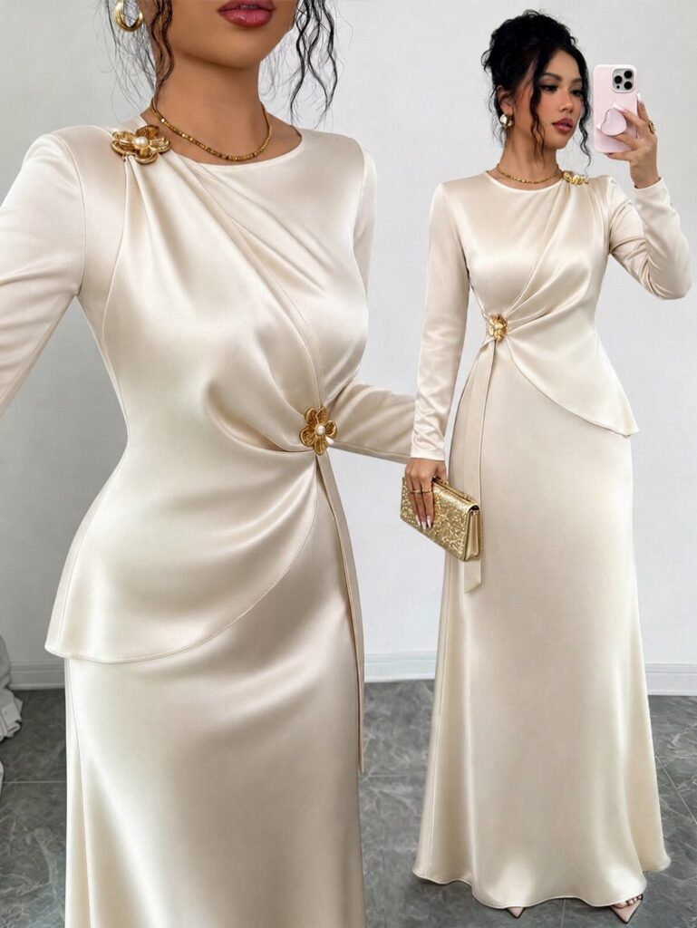 A woman posing in a cream satin long-sleeved evening gown with gold floral accents.