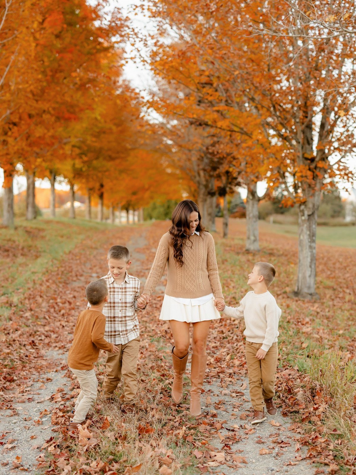 A woman and three children walking through an autumn forest wearing coordinated fall outfits.