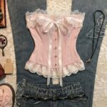 Pink lace corset and low-rise blue denim jeans laid on a white lace background.